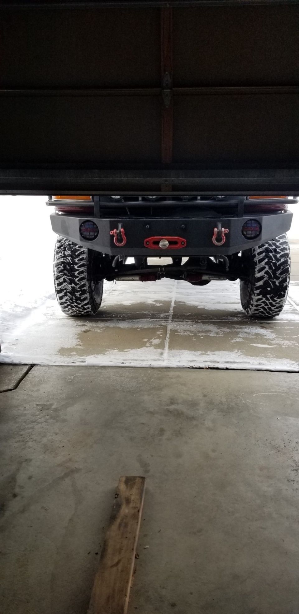 Rear view of a modified off-road vehicle with snow on tires and ground.