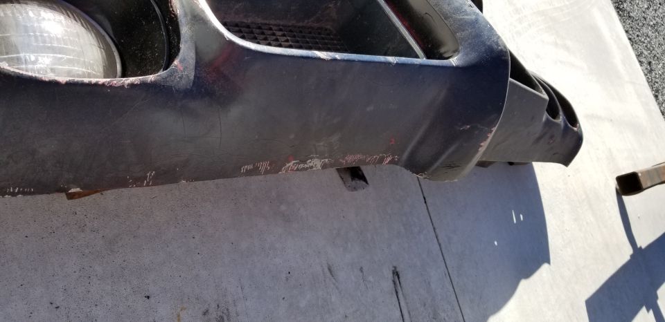 Black vehicle front bumper with scuff marks and red paint transfer.
