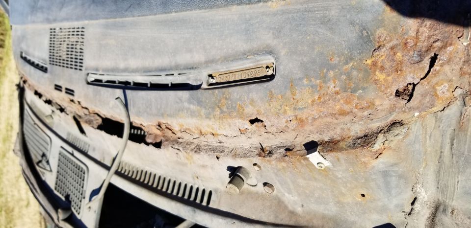 Heavily rusted vehicle cowl with VIN plate 242370L107285, vents, and wiring.
