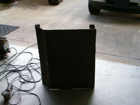 1979 Ford Bronco - A black skid plate sits on a concrete floor next to a grinder and electrical cords.