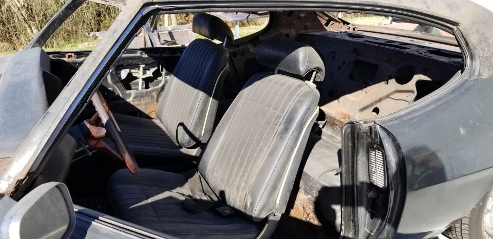 Interior of a 1970 Pontiac Firebird, showing front seats, dashboard area, and door panel