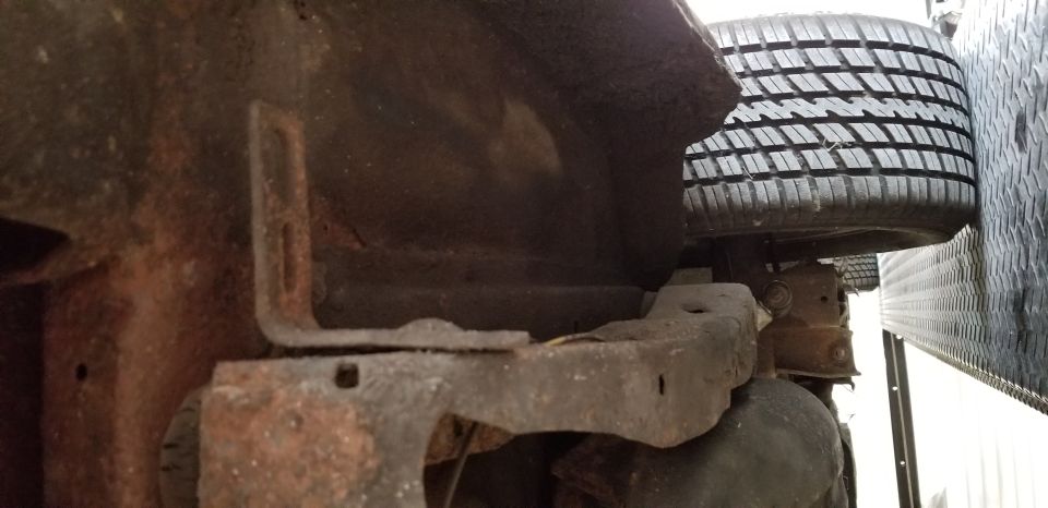 Undercarriage of a rusty vehicle with a spare tire mounted vertically