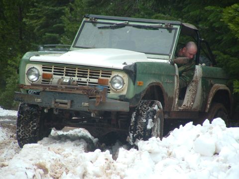 1990 Ford Bronco - Ford Bronco navigating a snowy trail with a driver visible inside.