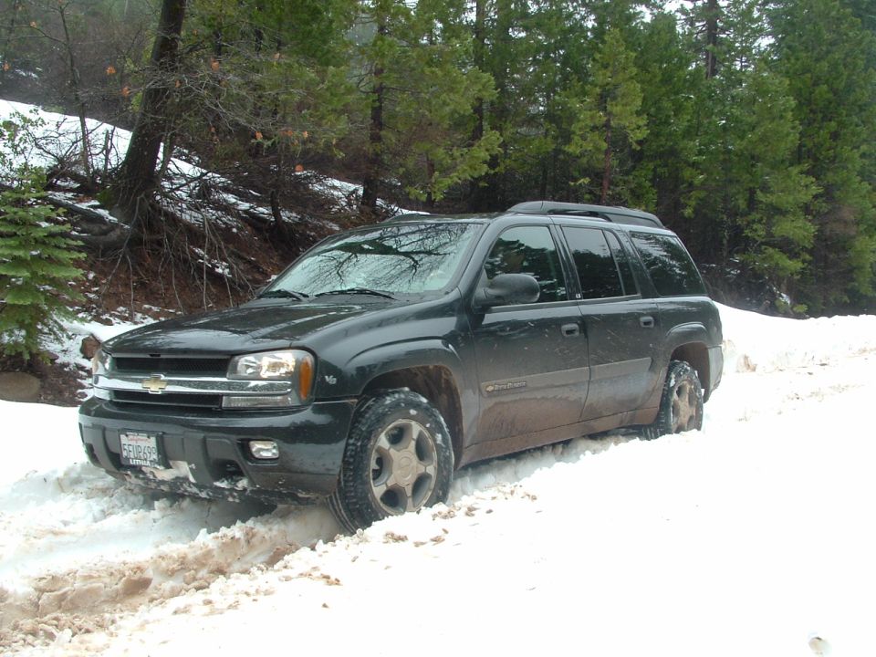 Black Chevrolet Trailblazer SUV stuck in snow, front-left tire deep in snow