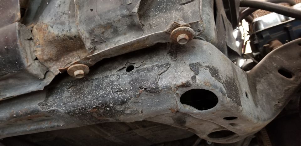 Close-up of a heavily rusted and corroded vehicle frame underside.