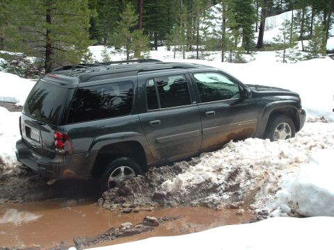 1990 Ford Bronco - This dark SUV is stuck in a muddy, snowy terrain, with its tires partially submerged.