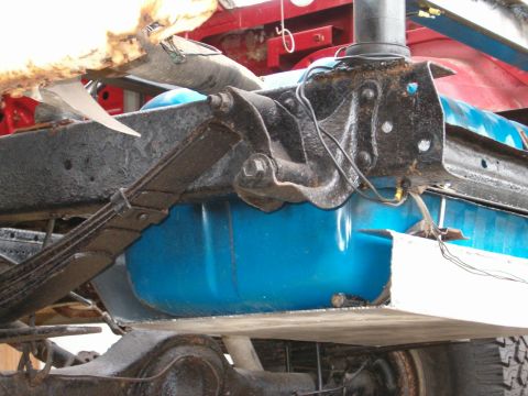 1979 Ford Bronco - Underside view of a vehicle's suspension and fuel tank, likely undergoing maintenance or repair.