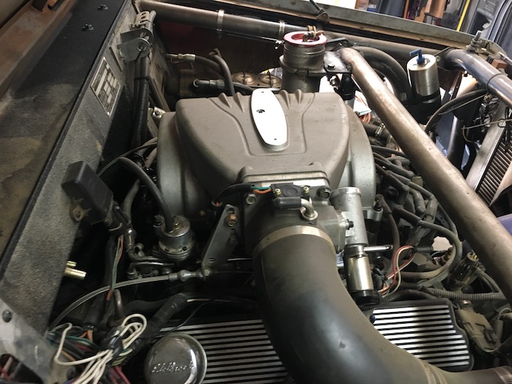 Engine bay with large grey intake manifold, hoses, and wiring.