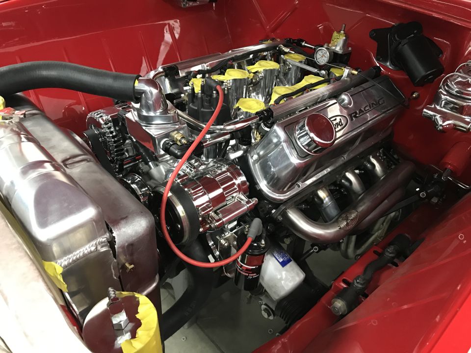Close-up of a shiny chrome Ford Racing engine in a red vehicle.