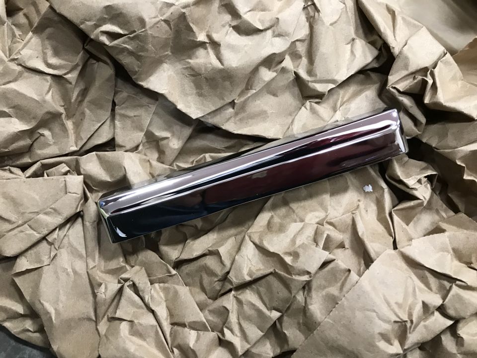 Shiny chrome trim piece on crumpled brown paper
