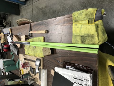 1964 Ford Fairlane - A workbench with various tools and materials, including a long metal rod covered in green tape, several microfiber cloths, and boxes of san…