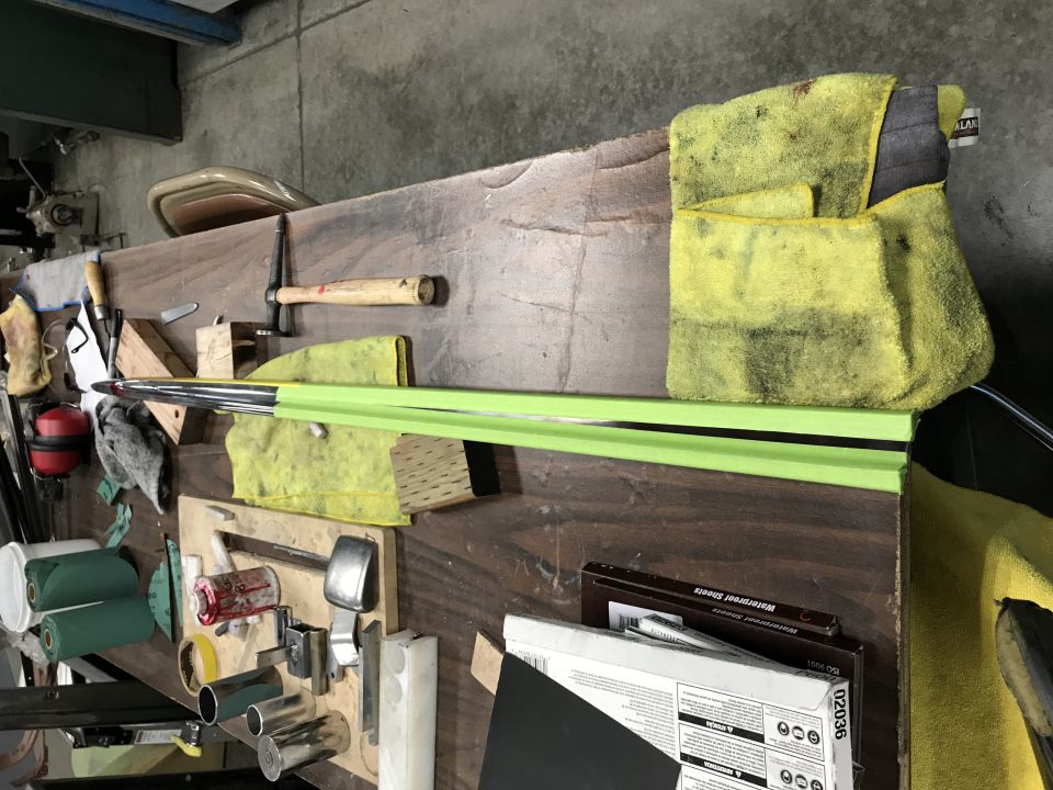 Workbench with tools and materials, including a metal rod with green tape and microfiber cloths.