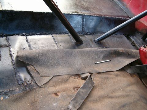 1979 Ford Bronco - Vehicle interior floor with exposed metal and partial rubber matting, showing roll bar mounts.