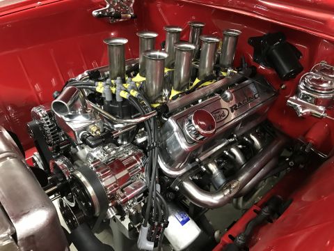 1964 Ford Fairlane - A highly polished chrome Ford Racing V8 engine is installed in a red vehicle. The engine features individual throttle bodies and yellow spa…