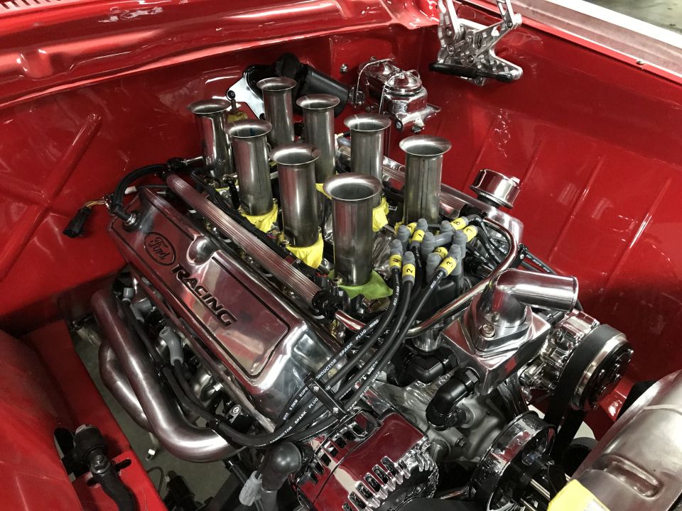 Polished Ford Racing V8 engine with individual throttle bodies in a red vehicle.