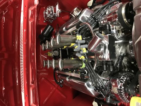 1964 Ford Fairlane - A highly polished chrome engine is installed in a red vehicle. The engine features individual throttle bodies and prominent spark plug wire…