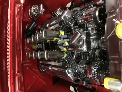 1964 Ford Fairlane - A highly polished chrome engine with individual throttle bodies is installed in a red engine bay. The engine features prominent exhaust sta…