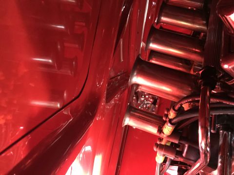 1964 Ford Fairlane - A close-up, angled view of the polished chrome intake trumpets and fuel lines of a performance engine, set against a glossy red background.