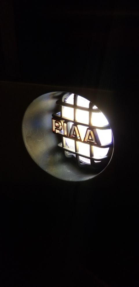 1996 Ford Bronco - A close-up shot shows the PIAA logo illuminated behind a black grille, likely on a vehicle's headlight or driving light assembly.