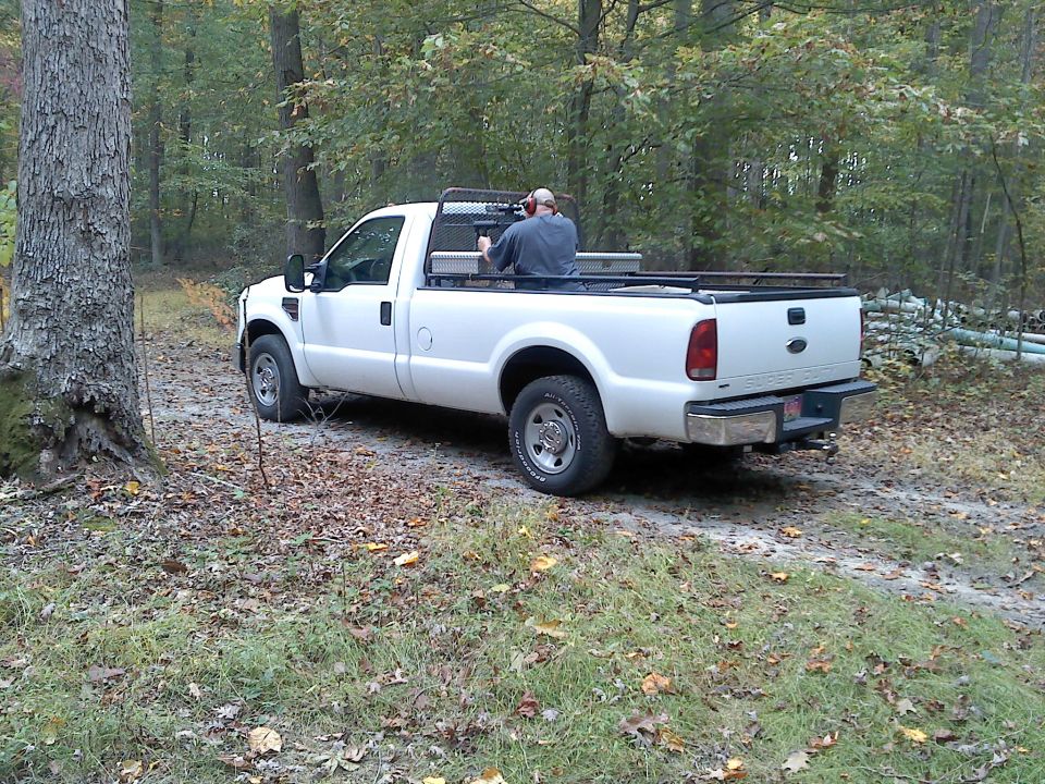 White Ford F-250 Super Duty pickup truck parked on a dirt road in the woods