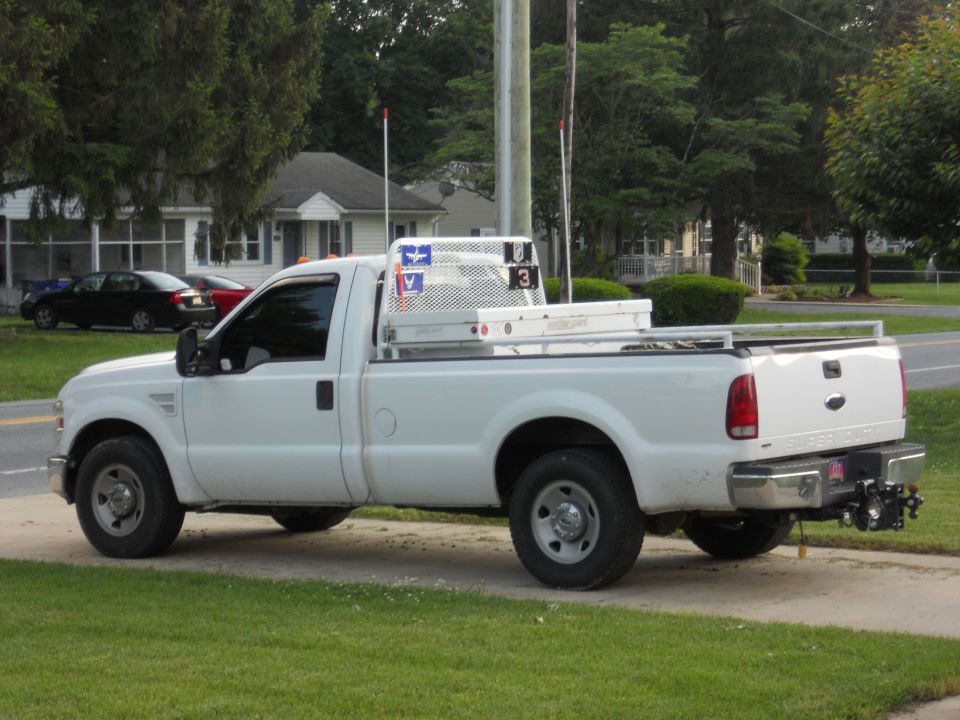 White Ford F-250 Super Duty pickup truck with a utility bed and toolbox, seen from the side