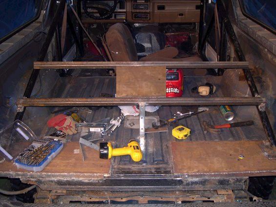 Interior of a vehicle with metal bars installed, tools like a drill, hammer, and tape measure are scattered around