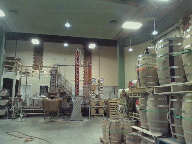 Distillery with large copper stills and stacks of wooden barrels