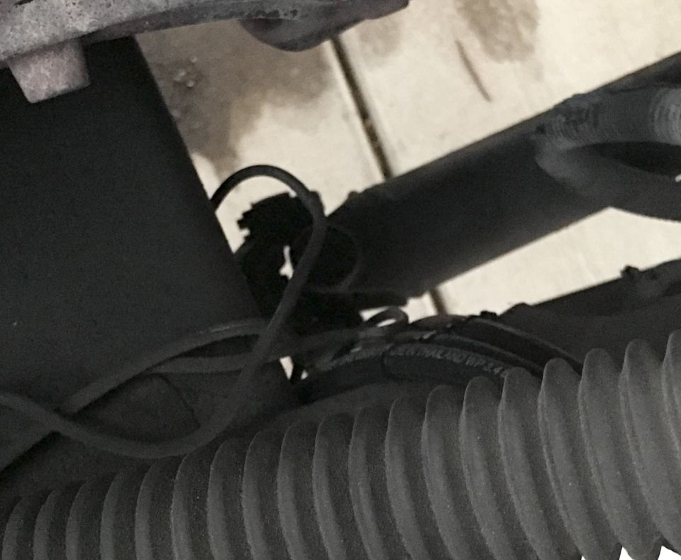 Close-up of a black rubber bellows and wiring harness, with part of a metal component above