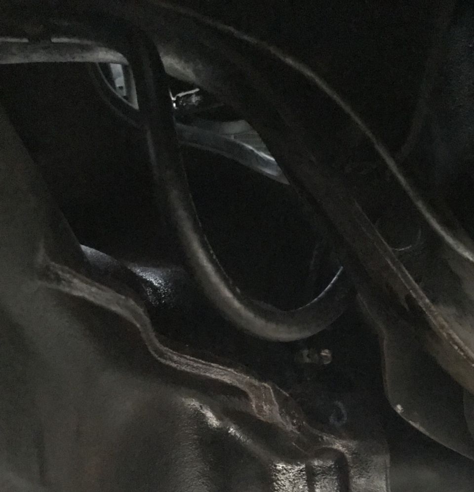 Close-up of dark metal tubing and engine block with stamped numbers.