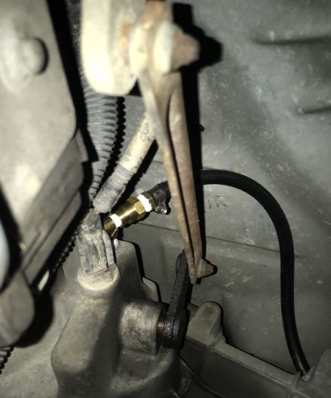 1995 Ford Bronco - A close-up view shows a brass fitting connected to a black hose, secured with a hose clamp. The fitting is attached to a component of what…