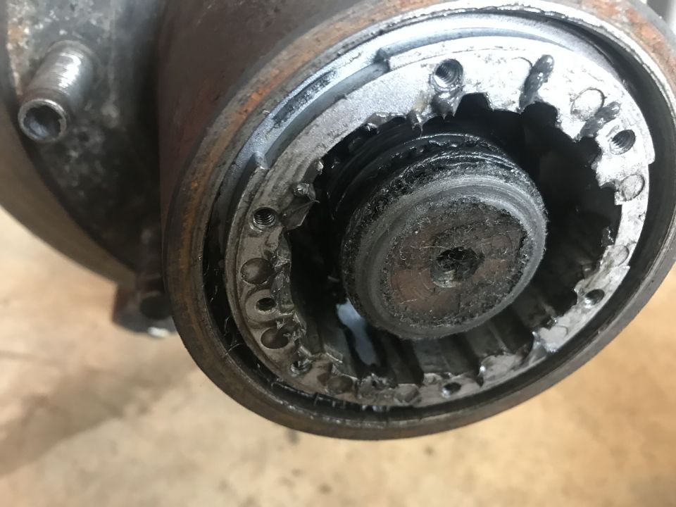 Damaged splined hub assembly with worn and broken splines and grease.