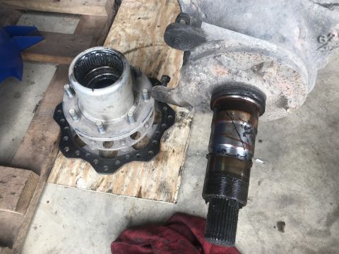1989 Ford Bronco - Disassembled vehicle axle and hub assembly components are laid out on a wooden surface.