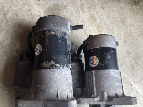 1993 Mazda MX-3 - Two starter motors, likely for a vehicle, are shown side-by-side on a concrete surface.