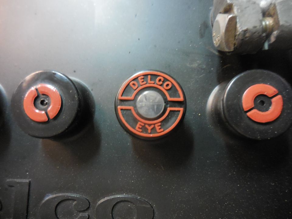 Three black circular parts with orange accents on a dark surface, one labeled "DELCO EYE".