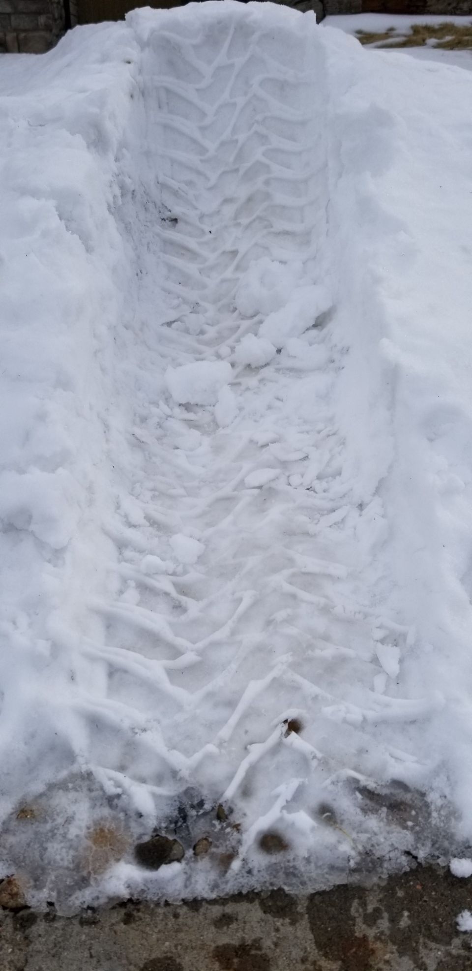 Tire tracks pressed into a snow-covered surface, showing tread patterns