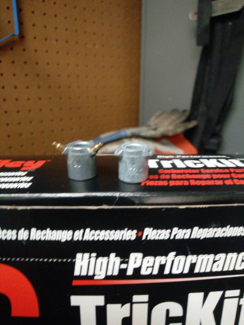 Two silver carburetor parts on a black box labeled High-Performance TrickKit