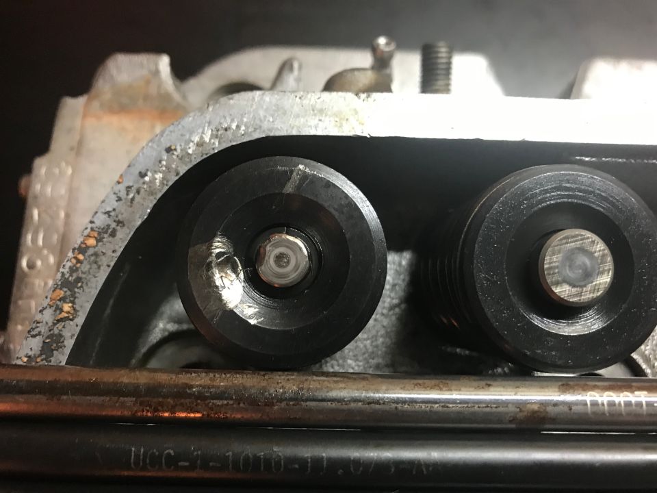Close-up of engine cylinder head valve train with damaged valve retainer.