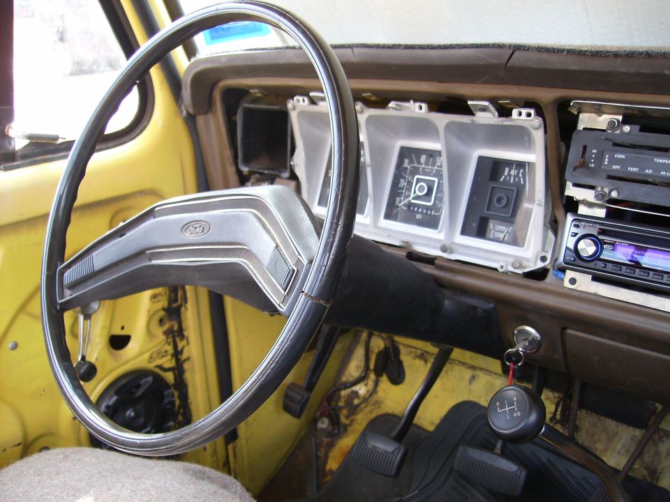 Ford truck interior showing steering wheel, dashboard, and gauges. The dashboard is yellow and brown
