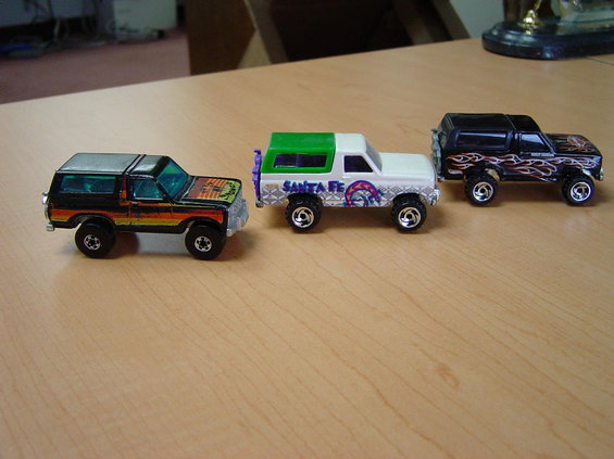 Three toy Ford Bronco models on a wooden table.