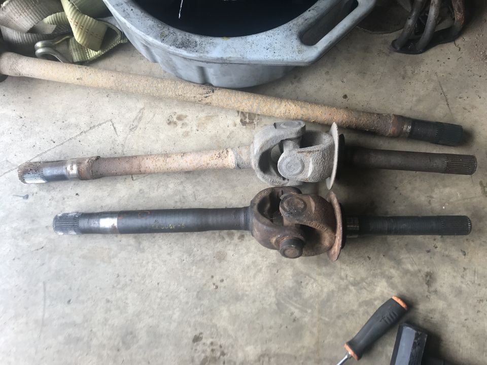 Two driveshafts with universal joints on a concrete floor.