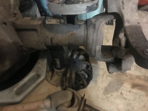 1989 Ford Bronco - Close-up view of the underside of a vehicle's drivetrain, showing the differential housing, suspension components, and a black hose with wh…