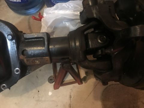1989 Ford Bronco - A close-up view of a vehicle's differential housing and driveshaft with a universal joint. The parts are black and appear to be made of cas…