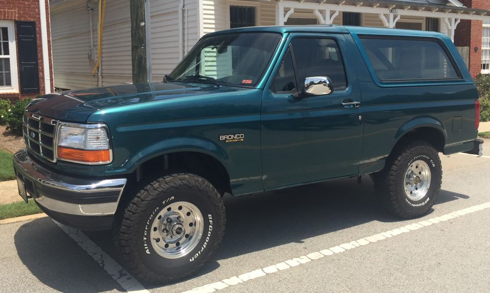1996 Ford Bronco parked curbside, side view, dark teal color, chrome accents, BFGoodrich tires.