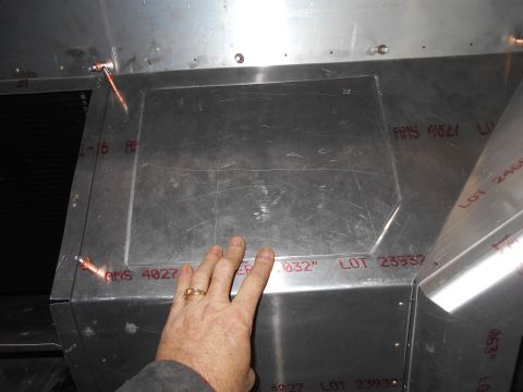 1992 Ford Bronco - A person's hand with a ring is touching a section of a metal structure, possibly part of a vehicle build. Red stenciled text indicating mat…