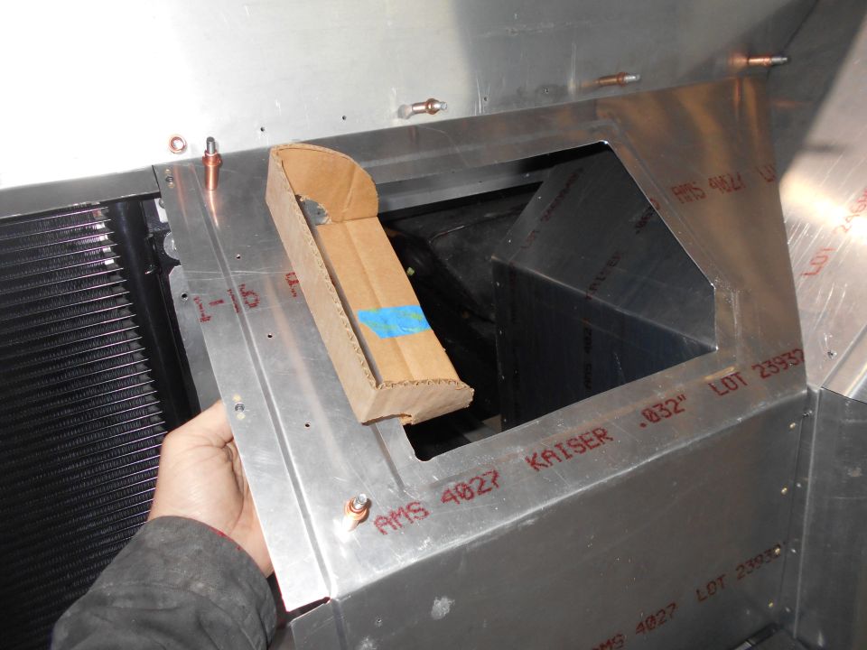 Cardboard piece held over opening in aluminum structure with red lettering.