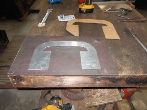 1992 Ford Bronco - A metal template is placed on a workbench next to a cardboard template of the same shape. Tools and other workshop items are scattered arou…