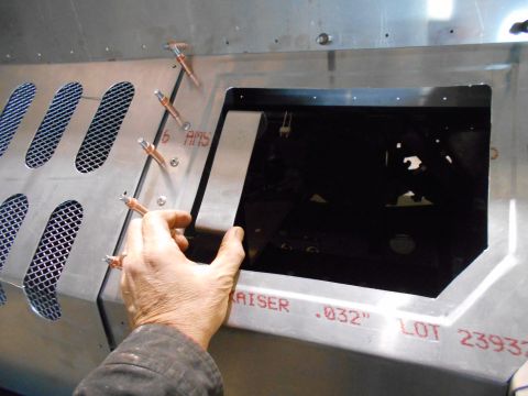 1992 Ford Bronco - A person's hands are shown installing a metal bracket into a larger metal assembly. The bracket has a brushed metal finish and the assembly…