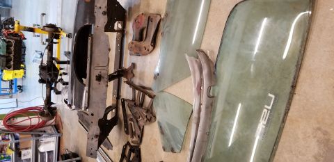 1970 Pontiac GTO — Car parts including engine, axle, glass panels, and metal body panels on a concrete floor.