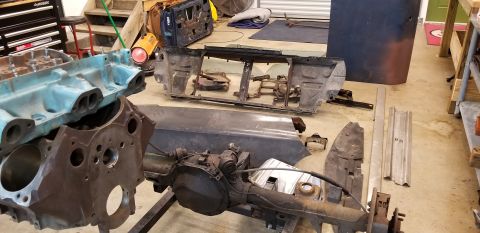 1970 Pontiac GTO — Disassembled car engine block, differential, and body parts on a garage floor.