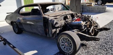 1970 Pontiac GTO coupe, disassembled, engine exposed, hood open, parked outdoors.